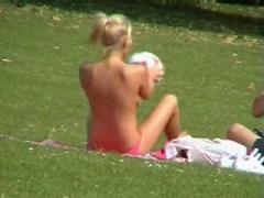 Middle-aged Female Nudist Sunbathing Naked On The Grass In A City Park